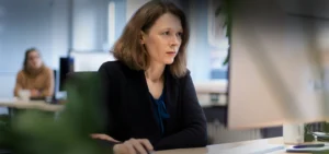 Frau mit schwarzem Blazer sitzt konzentriert vor einem Monitor